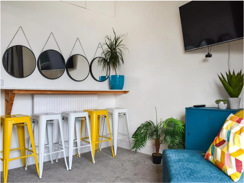 Photo of dressing table with yellow and white high stools and round mirrors